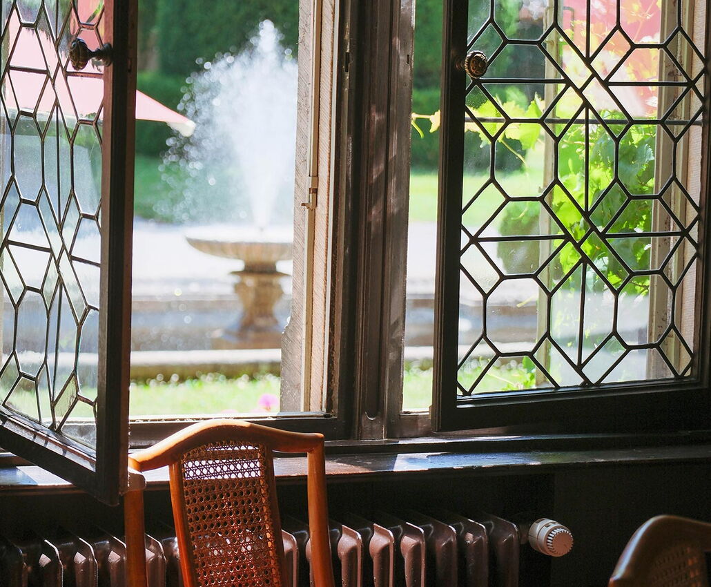 Blick aus einem historischen Fenster von Schloss Rauischholzhausen auf den Springbrunnen des Vorplatzes